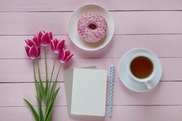 Fototapeta na wymiar Spring Flat lay.Spring to-do list.International Women's Day. pink tulips flowers, blank notebook, cup of tea and pink donut on a pink wooden background.top view, copy space.