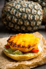 Hawaiian vegan burger with grilled pineapple, guacamole and grilled bell pepper. Selective focus. Shallow depth of field.