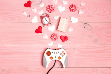 Joystick with romantic decorations on pink wooden background. Holidays gaming concept. St. Valentines Day concept.