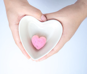 Fototapeta premium One of Kleeb Lamduan,Thai shortbread cookies heart shape in white ceramic bowl heart shape holding by hand on white background for love issue.