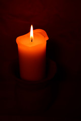 Candle flame burning in darkness on wall background. Advent or memorial prayer candle flame.