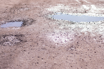 old road with stones, sand and puddles