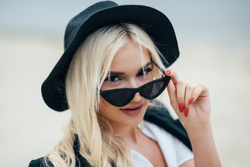 Cute blonde girl in glasses walks along the coast and enjoy life.