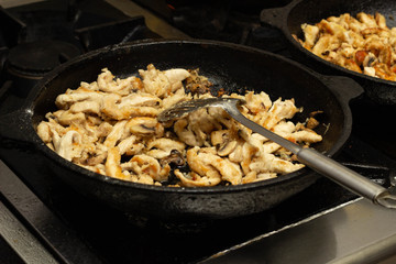 Beef meat with mushrooms fried in a pan, close-up, background, slow motion, kitchen