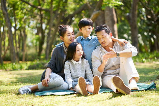 asian family with two children chatting park