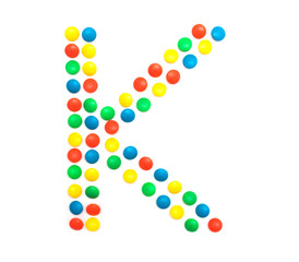 Multi-colored vitamins pills that are lined with the letter Vitamin K, close-up