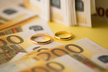 Golden wedding rings on banknotes background. Marriage of convenience