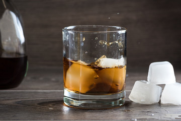 Glass of whiskey and splashing from falling ice