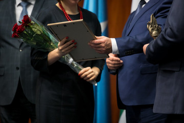 Business award. Mature businessman congratulates younger employee standing in front of the happy team