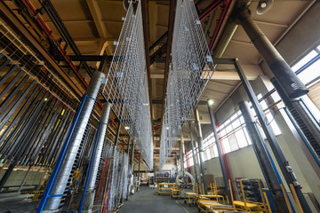 Metal parts are suspended on an overhead conveyor. Line painting in an electrostatic field