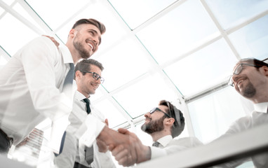 bottom view. handshake employees over the Desk