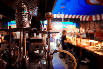 Hookah close-up in a cloud of smoke on a dark blurred background of the bar.