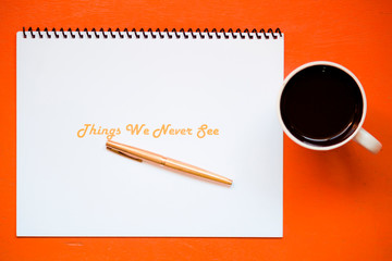 Escritorio de Oficina con una libreta de notas de hojas blancas bajo un lapicero - pluma dorada y junto a una taza blanca de café  en el trabajo 