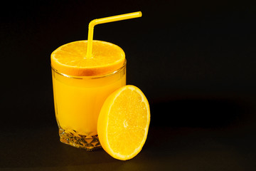 Fresh healthy orange juice in a glass with citrus around on black background