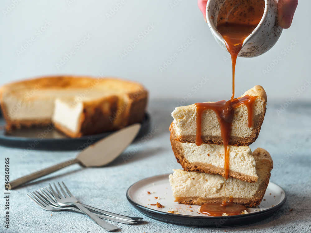 Wall mural caramel pouring on stack of three cheesekace pieces. cheesecake with caramel on gray cement backgrou