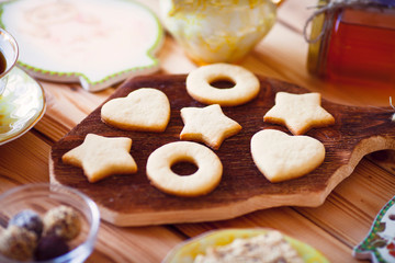 Beautiful set of homemade cookies stars and hearts on the brown decorative board, vintage cup of tea and honey. Sunny morning. Food, break, cooking, lifestyle concept. Top view. Close up.