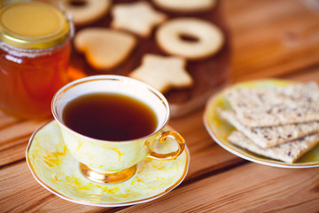 Vintage cup of tea with natural sweets and jar of honey on the wooden background. Sunny morning.  
