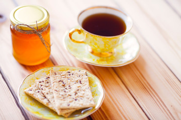 Vintage cup of tea with natural sweets and jar of honey on the wooden background. Sunny morning.  
