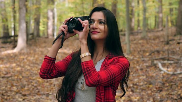 Happy female photographer in  forest taking photos of the beautiful trees fall colors 