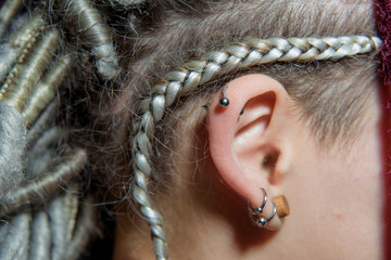 Piercing. The human ear. Dreadlocks on the hair. Pointed earring for piercing. Pierced ear. Neck....