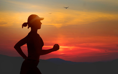 young fit and attractive woman in American cap training on sunset doing running fitness workout under a beautiful orange sky in sport exercise and healthy lifestyle
