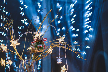 Golden branches in a vase with Christmas decorations and a garland on a blue background