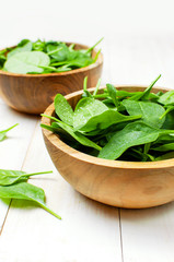 Fresh green spinach leaves on wooden bowl on white wooden rustic background Selective focus copy space. Baby young spinach leaves, Ingredient for salad, healthy food, diet. Nutrition concept.