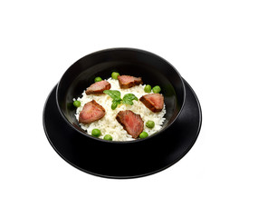 Rice with meat pieces, basil and green peas in a plate on a white background. 