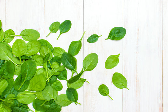Fresh green spinach leaves on white wooden rustic background top view copy space. Baby young spinach leaves, Ingredient for salad, healthy food, diet. Nutrition concept.