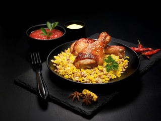 grilled chicken legs with sesame and rice on a black background.