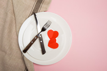 Festive table setting for Valentine's Day with fork, knife,  hearts on a red background. Top view. - Image.
