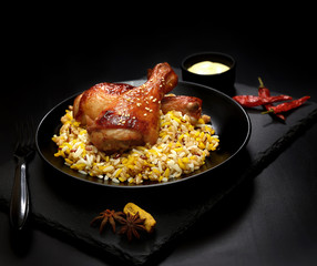 grilled chicken legs with sesame and rice on a black background.