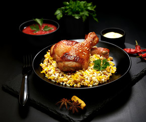 grilled chicken legs with sesame and rice on a black background.