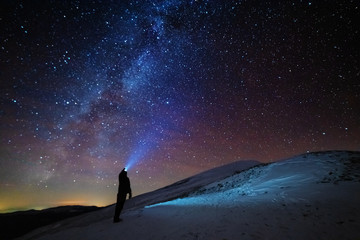 A charming night in the Carpathian Mountains with a tourist in a red tent and a Milky way with...