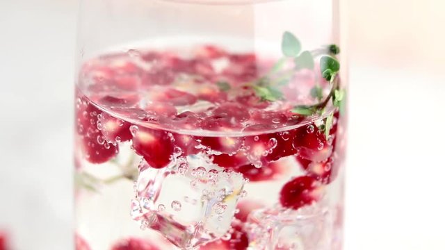 Festive drinks, gin and tonic pomegranate cocktail or detox water with ice. Selective focus, copy space for text, light gray concrete table surface.
