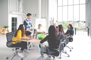 Group of young asian creative team talking, brainstorming, sharing or training on meeting or workshop at office. Happy asian workplace sitting attentive together in rear view concept with soft tone.