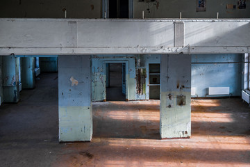 Old abandoned building of the Soviet manufactory. Empty room with columns. Daylight