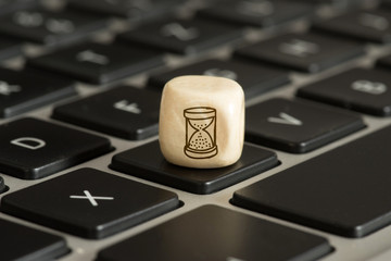 Ein Computer und ein Würfel mit dem Symbol für eine Sanduhr