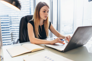 Young woman working on laptop studying financial data and statistics of the company