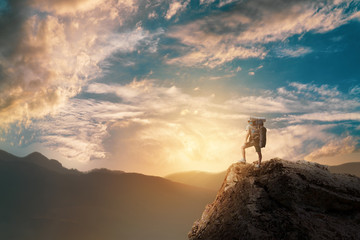 Hiker with backpack standing on top of a mountain and enjoying.