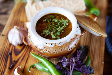 Delicious hearty soup with meat in a traditional pot on the table in the restaurant.