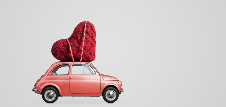 Living coral retro toy car delivering craft heart for Valentine's day on gray background