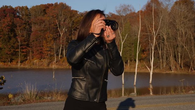 Female photographer in the park taking photos of the fall colors