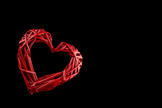 Red Heart with a hole woven from a vine. Valentine's day. Isolated On black background.