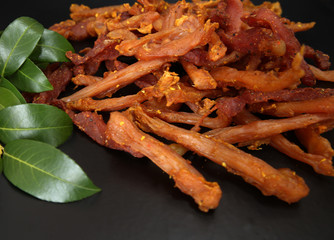 jerky meat on a black background with bay leaves
