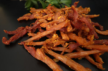 dried chicken meat on a black background with bay leaves