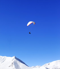 Fototapeta na wymiar Paraglider in snowy winter mountains at sun day