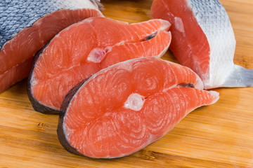 Uncooked salmon steaks on wooden cutting board close-up