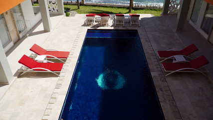 luxury hotel with swimming pool, sun beds, palm trees by sea. tropical resort with pool. Travel concept.