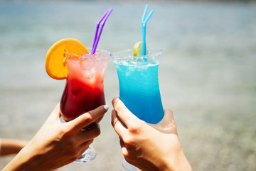 Beautiful girls drinking cocktails during summer vacation on beach